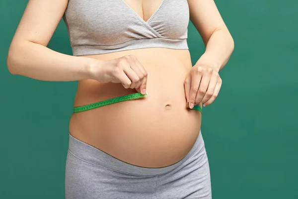 Terhes nő mérőszalaggal méri a gyomrot — Stock Fotó
