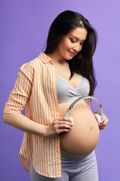 Femeile gravide care folosesc căști, își permit bebelușul nenăscut să asculte muzică clasică . — Fotografie, imagine de stoc