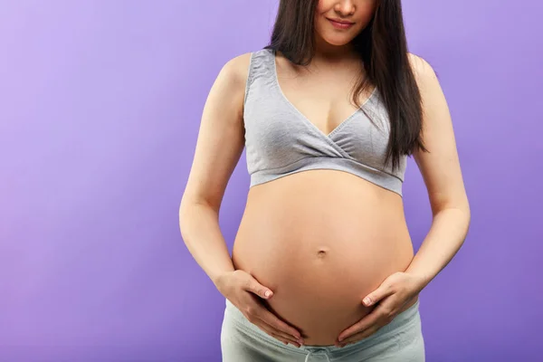 Amar a la mujer embarazada sosteniendo su vientre mientras posa en el estudio — Foto de Stock