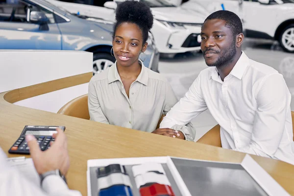 professional sales agent and clients have friendly conversation in dealership