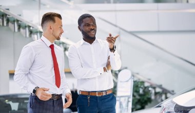 Afrikalı bir adam ilgilendiği araba hakkında sorular soruyor.