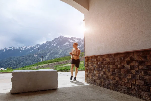 Ung idrottsman i sportiga shorts som springer under träningen utomhus — Stockfoto