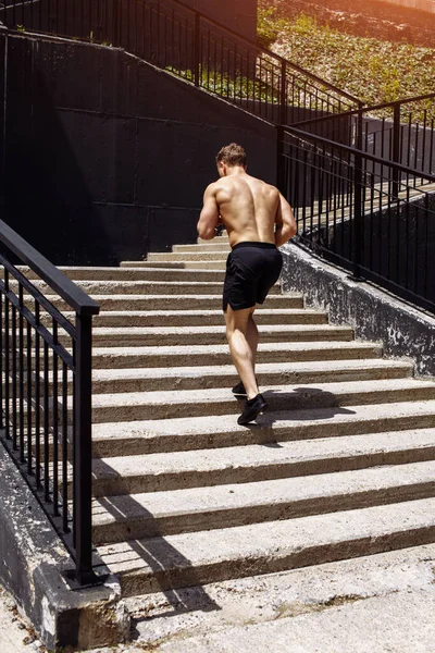 Biały sportowiec biegnie w górę z energią po miejskich schodach — Zdjęcie stockowe