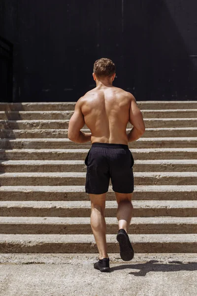 Hombre de fitness corriendo por los escalones bajo un paso elevado —  Fotos de Stock