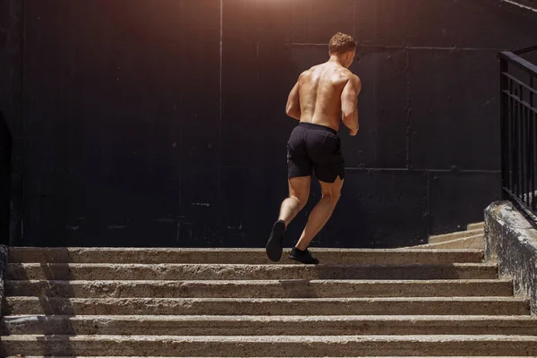 Deportista caucásico corriendo hacia arriba con energía en la escalera urbana — Foto de Stock