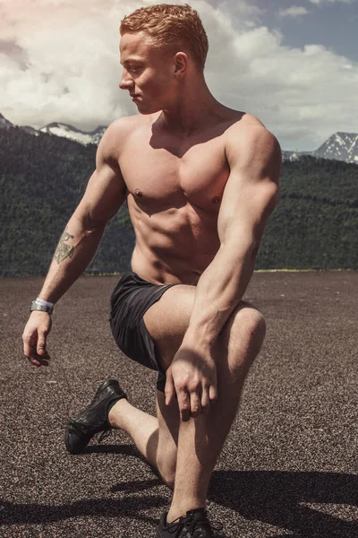 Jovem fisiculturista mostrando músculos forma ao ar livre — Fotografia de Stock