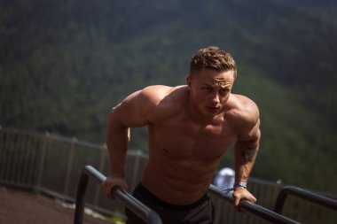 Motivasyonlu sporcu vücut ağırlığı yapar. Dağlık alanda açık spor salonunda şınav çeker..