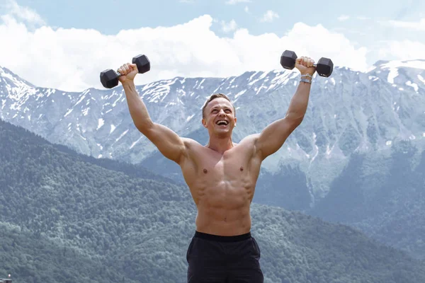 Atleta masculino muscular com braços levantados fazendo exercícios de elevação halteres . — Fotografia de Stock