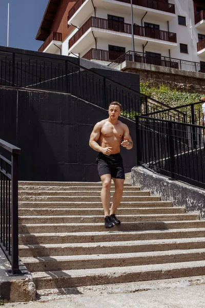 Vit tröjlös atletisk löpare springer upp och ner för trapporna i staden. — Stockfoto
