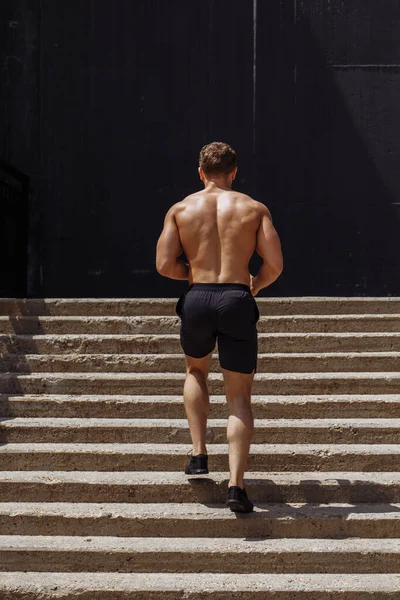 Deportista caucásico corriendo hacia arriba con energía en la escalera urbana — Foto de Stock