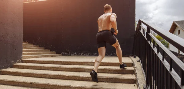 Deportista caucásico corriendo hacia arriba con energía en la escalera urbana — Foto de Stock