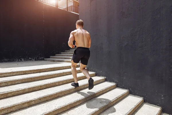 Deportista caucásico corriendo hacia arriba con energía en la escalera urbana — Foto de Stock