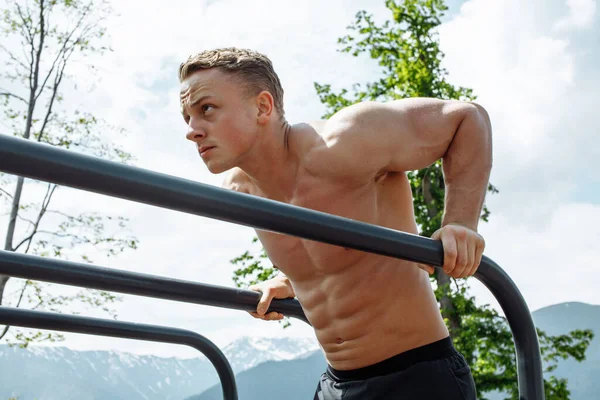 Motivált sportoló férfi csinál testsúly push up a hegyvidéki területen szabadtéri edzőterem. — Stock Fotó