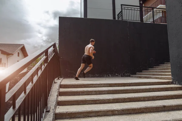 Deportista caucásico corriendo hacia arriba con energía en la escalera urbana — Foto de Stock