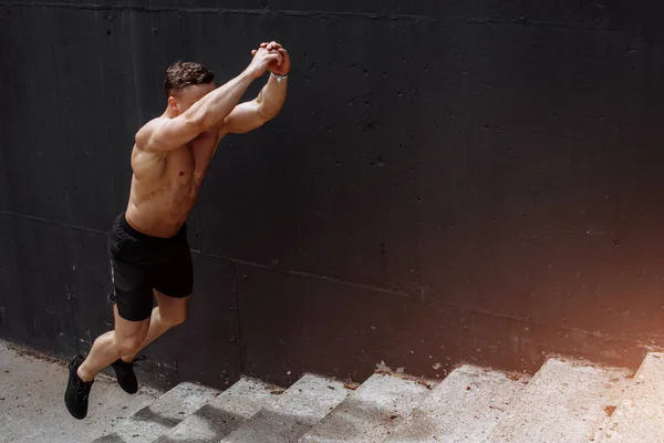 Joven atleta saltando arriba en la escalera y calentando antes de correr — Foto de Stock