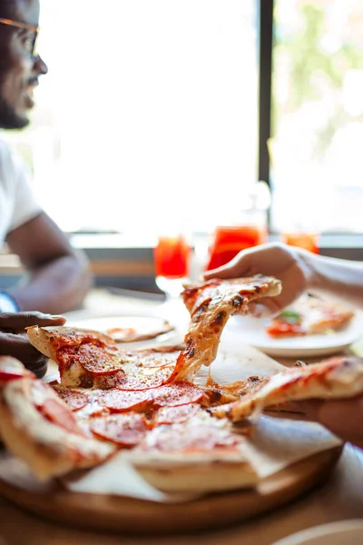 Primer plano de la gente manos tomando rebanadas de pizza de pepperoni en la cafetería, vista superior. — Foto de Stock