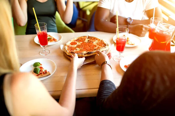Vista superior de la mano de la gente y comer deliciosa pizza en el restaurante, de cerca — Foto de Stock