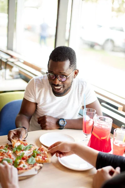 Afrikai amerikai férfi ül a pizzériában és a barátaival ebédel a kávézóban.. — Stock Fotó