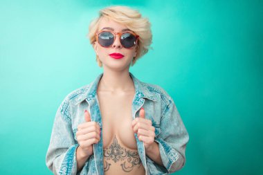 Göğüs altında dövmesi olan kot ceketli seksi kadın. Rock Yıldızı