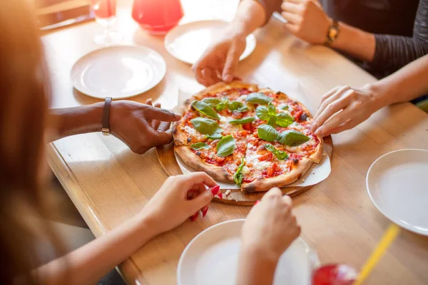 Közelkép az emberek kezét vesz szeletek pepperoni pizza kávézóban, felső nézet. — Stock Fotó