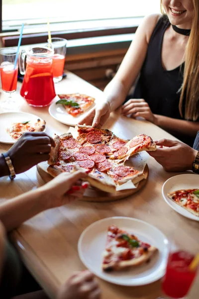 Primer plano de la gente manos tomando rebanadas de pizza de pepperoni en la cafetería, vista superior. — Foto de Stock