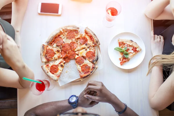 Közelkép az emberek kezét vesz szeletek pepperoni pizza kávézóban, felső nézet. — Stock Fotó