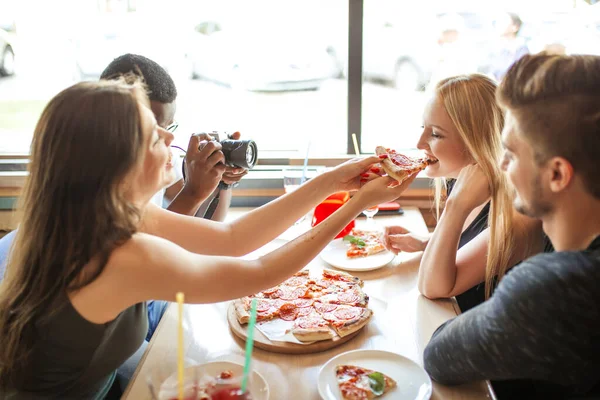 Fiatal, változatos barátok etetik egymást pizzával a kávézóban. — Stock Fotó