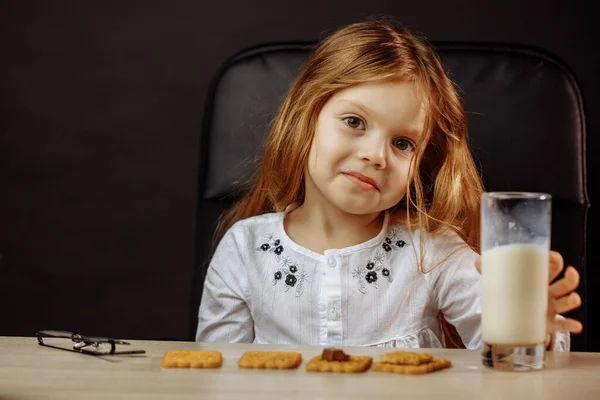 Menina bonita feliz fazendo um lanche com leite e biscoitos — Fotografia de Stock