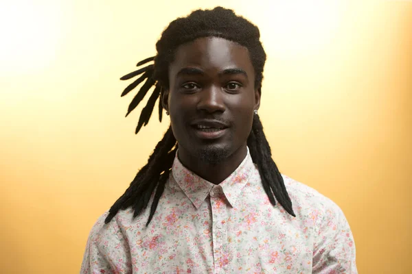 Junger gutaussehender afrikanischer Mann trägt Blumen-Hemd vor gelbem Hintergrund — Stockfoto