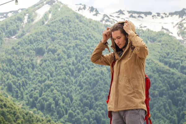 Man Utazó piros hátizsák pihentető szabadban sziklás hegyek a háttérben — Stock Fotó