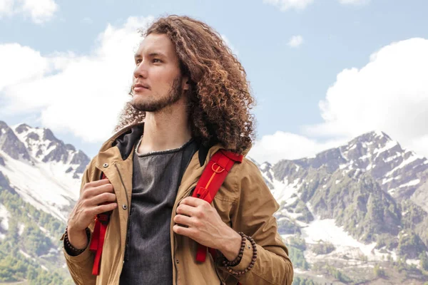 Muž Cestovatel s červeným batohem relaxační venkovní s skalnatými horami na pozadí — Stock fotografie