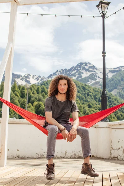 Glücklicher Mann, der sich in der Hängematte auf dem Gipfel des Berges entspannt. Sommerurlaub Reise Lifestylekonzept — Stockfoto