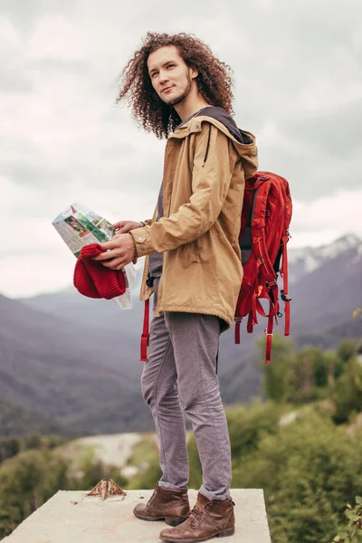 지도와 붉은 배낭을 든 사람, 뒤에 바위투성이의 산들이 있는 옥외를 찾는 사람 — 스톡 사진