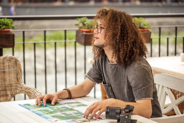 Männlicher Reisender mit lockigem Haar, der Karte und Suchweg in der Hand hält — Stockfoto