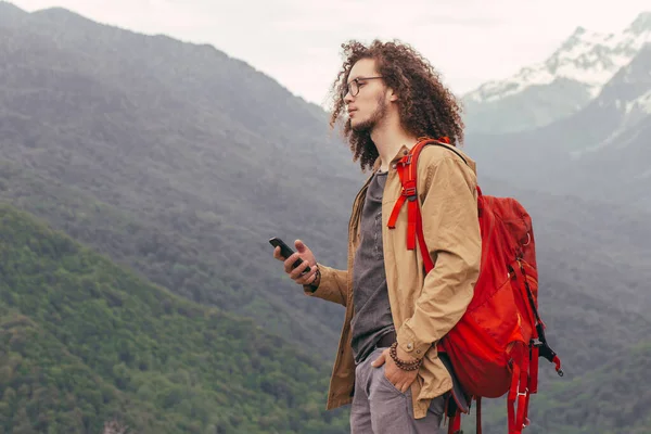 Muž odpočívající během pěší túry posezení a prohlížení telefonu — Stock fotografie