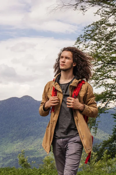 Homem viajante com mochila vermelha relaxante ao ar livre com montanhas rochosas no fundo — Fotografia de Stock