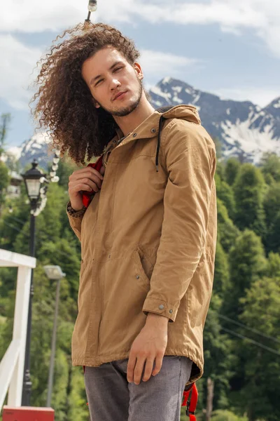 Mann mit rotem Rucksack blickt auf Kamera im Freien mit felsigen Bergen im Hintergrund — Stockfoto