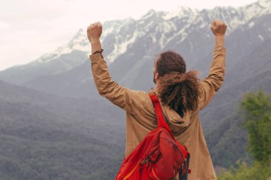 Sırt çantalı gezgin el kaldırdı. Arkaplanda dağlar