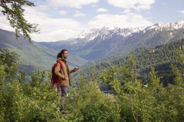 Yürüyüş sırasında dinlenen bir adam oturur ve telefonunu karıştırır.
