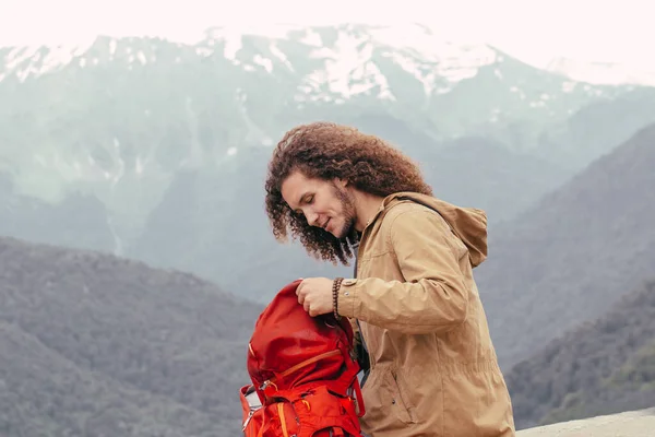 Homem mochila de embalagem para caminhadas com montanhas no fundo — Fotografia de Stock