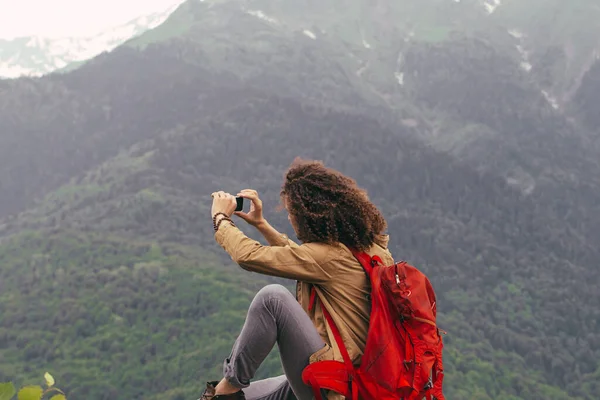 Man neemt foto met mobiele telefoon zittend op rots — Stockfoto