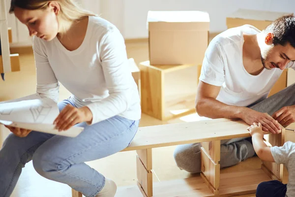 Pareja instalando muebles en casa nueva con instrucciones — Foto de Stock