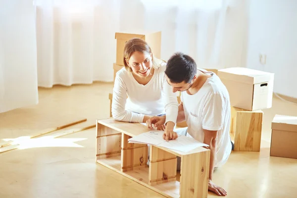 Pareja instalando muebles en casa nueva con instrucciones — Foto de Stock