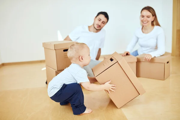 Niño pequeño que lleva la caja en movimiento, los padres en un fondo borroso. Concepto móvil —  Fotos de Stock