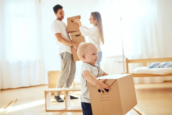 Niño pequeño que lleva la caja en movimiento, los padres en un fondo borroso. Concepto móvil —  Fotos de Stock