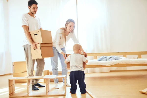 little boy carrying moving box, parents on blurred background. Moving concept