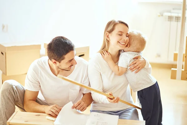 Famille avec garçon assembler des meubles à la maison, mère et fils câlins après la finition assembler — Photo