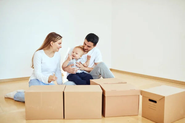 Familj med pojke packa upp flyttbara kartonger på nytt hem — Stockfoto