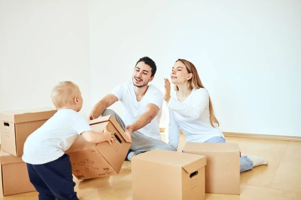 Familia con niño desempacando cajas de cartón móviles en un nuevo hogar — Foto de Stock