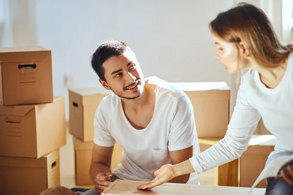 Paar montagemeubelen in nieuw huis, verhuisdozen op achtergrond — Stockfoto